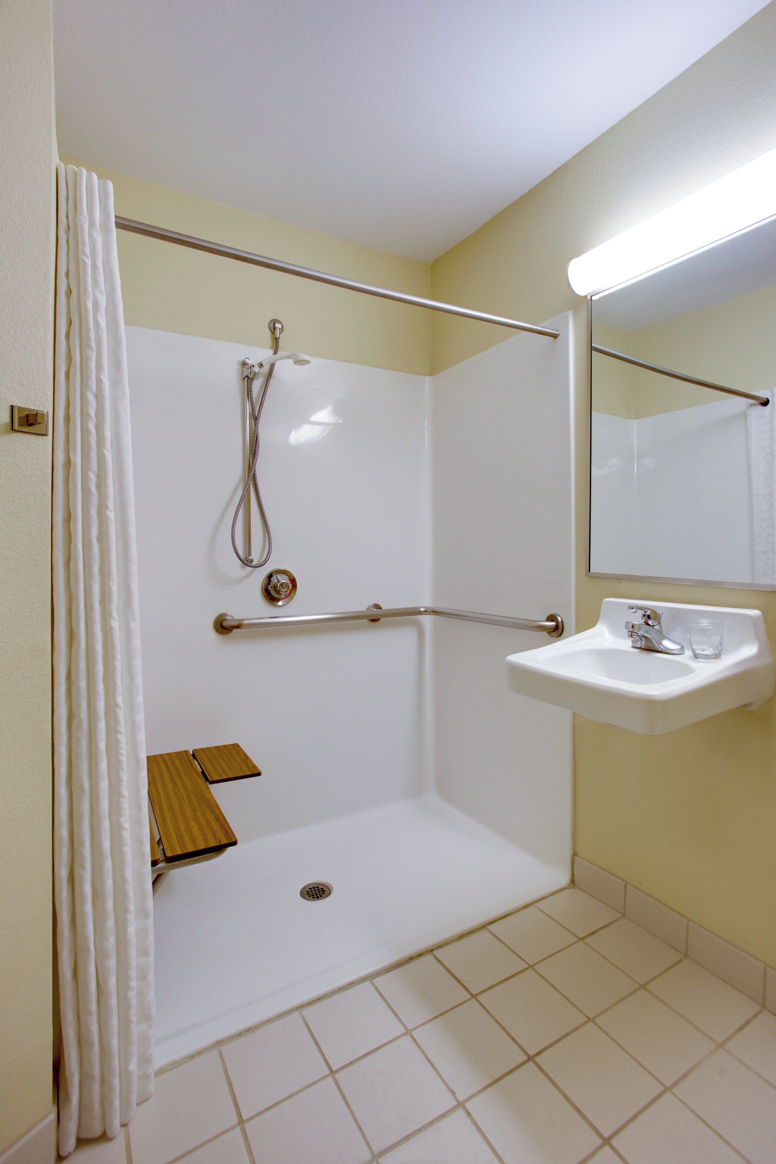 Un baño con ducha, lavabo y espejo.