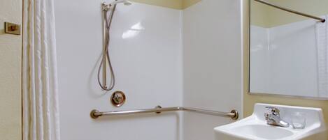 Un bagno con doccia, lavandino e specchio.