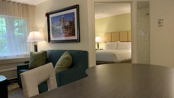 Een hotelkamer met een bed, een bureau, een stoel en een raam met gordijnen.
