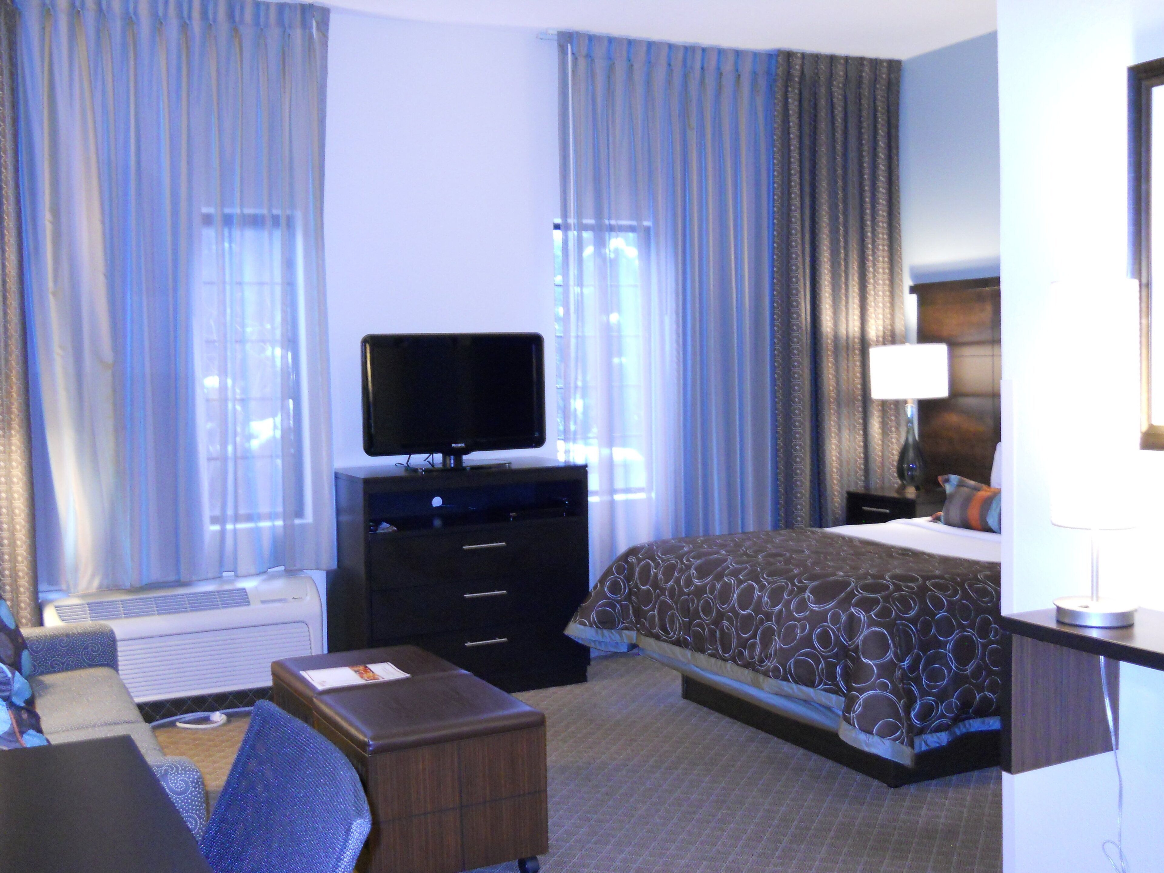Una habitación de hotel con una cama, un televisor en una cómoda, un escritorio y una silla.
