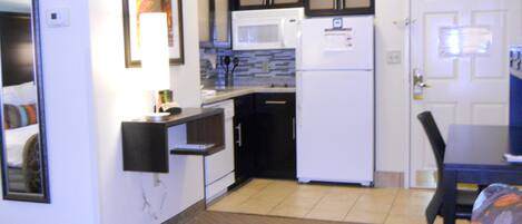 A compact kitchen with a microwave, refrigerator, and a small countertop.
