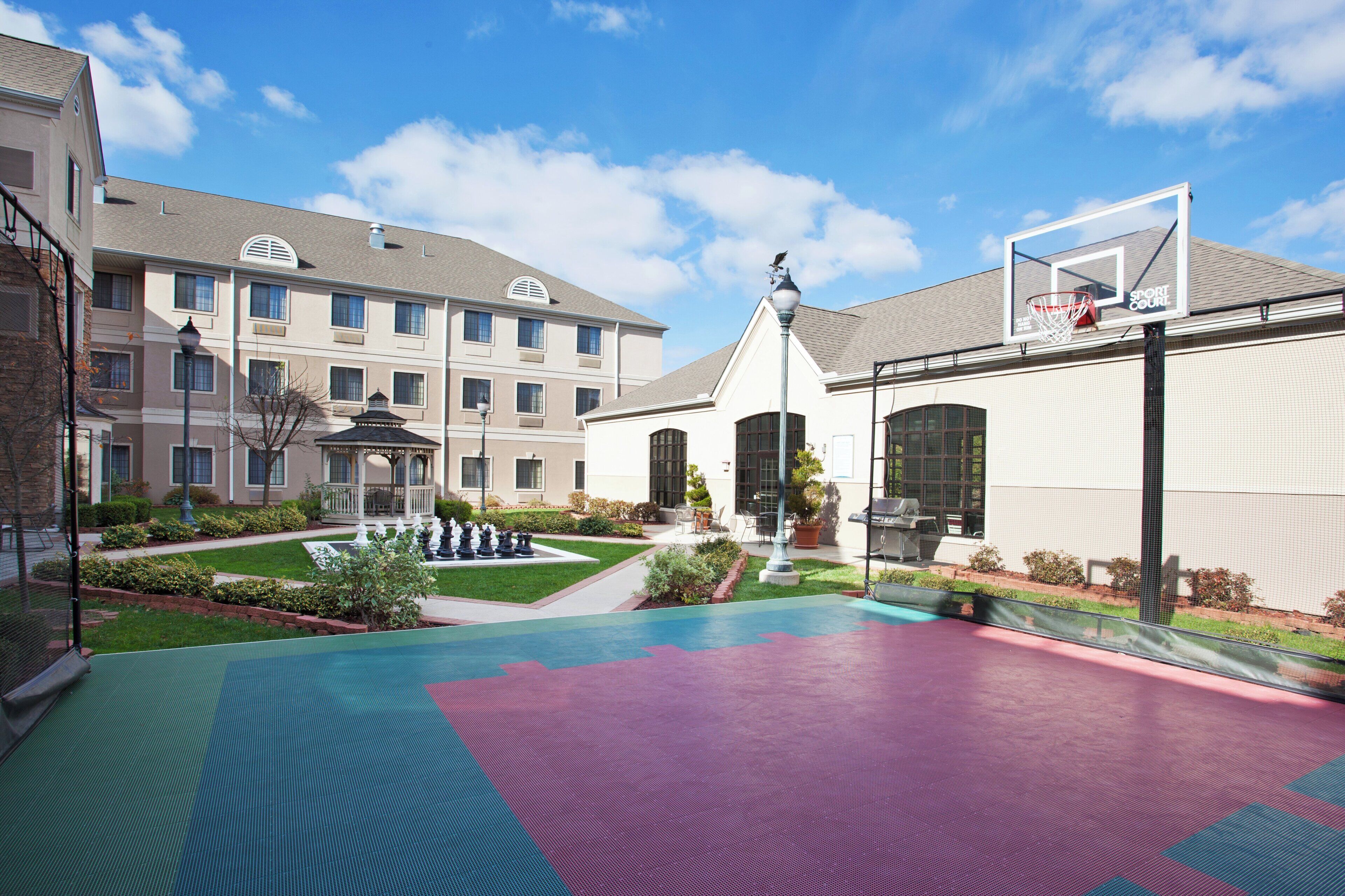 A courtyard with a basketball court, a gazebo, and a building with multiple windows.