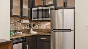 Una cocina moderna con armarios oscuros, electrodomésticos de acero inoxidable y una encimera de granito.