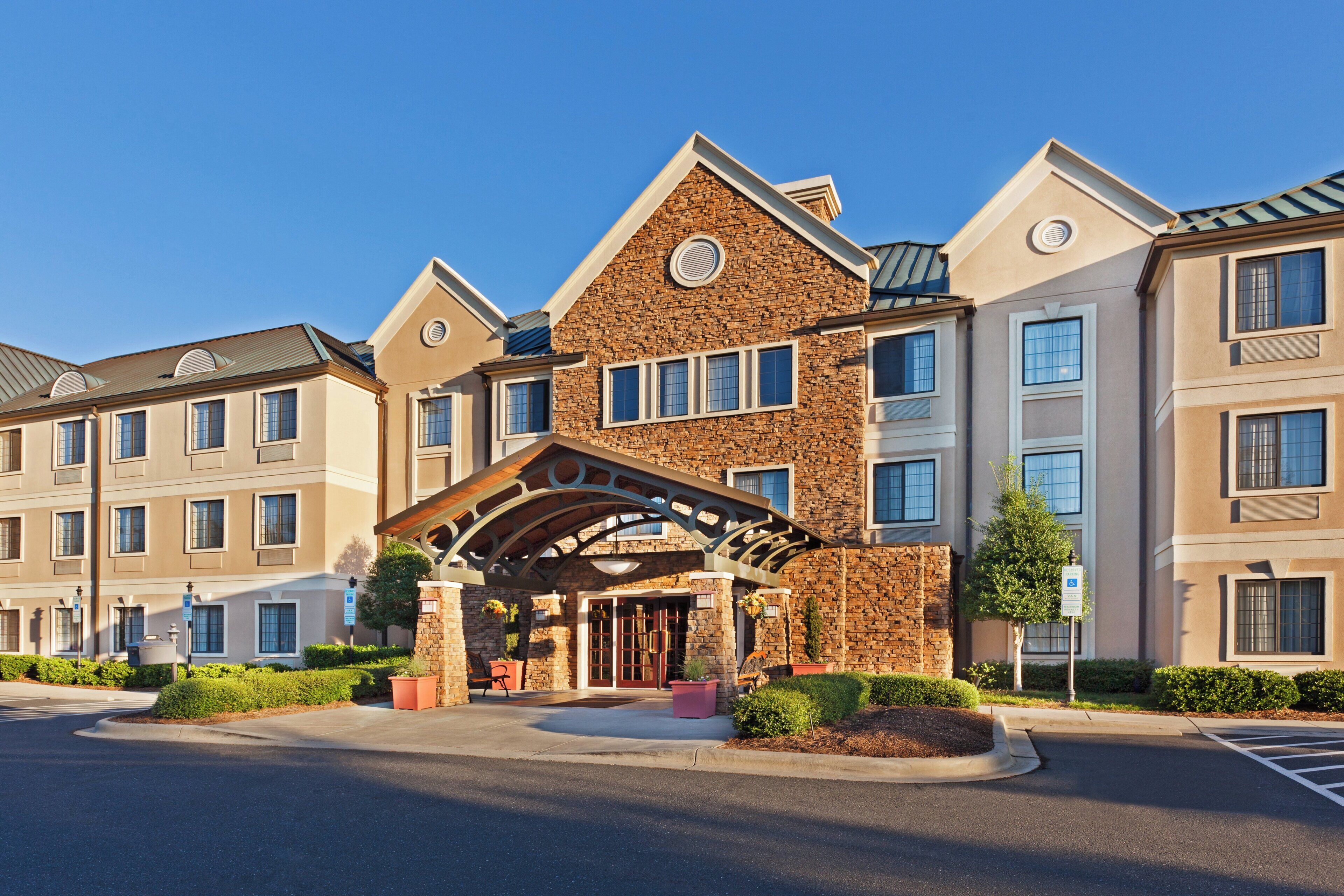 A multi-story hotel with a stone facade, a covered entrance, and a parking lot.