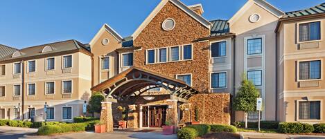 A multi-story hotel with a stone facade, a covered entrance, and a parking lot.