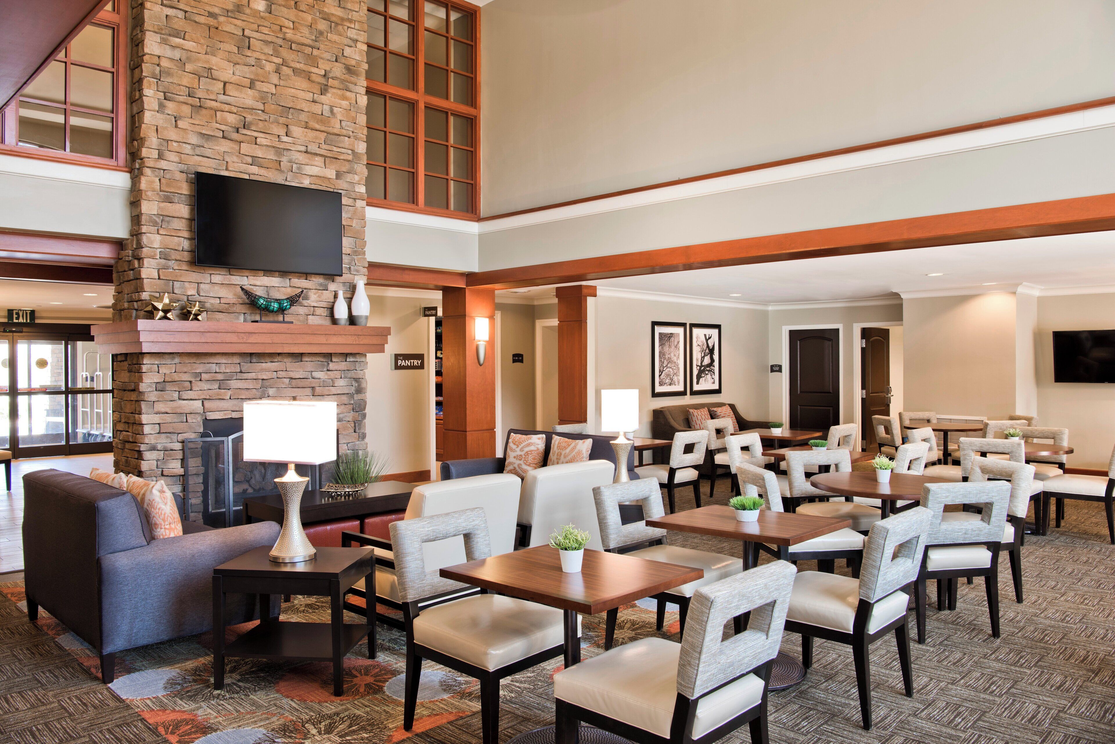 A hotel lobby with a fireplace, seating area, and a television mounted on the wall.