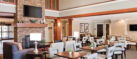 A hotel lobby with a fireplace, seating area, and a television mounted on the wall.