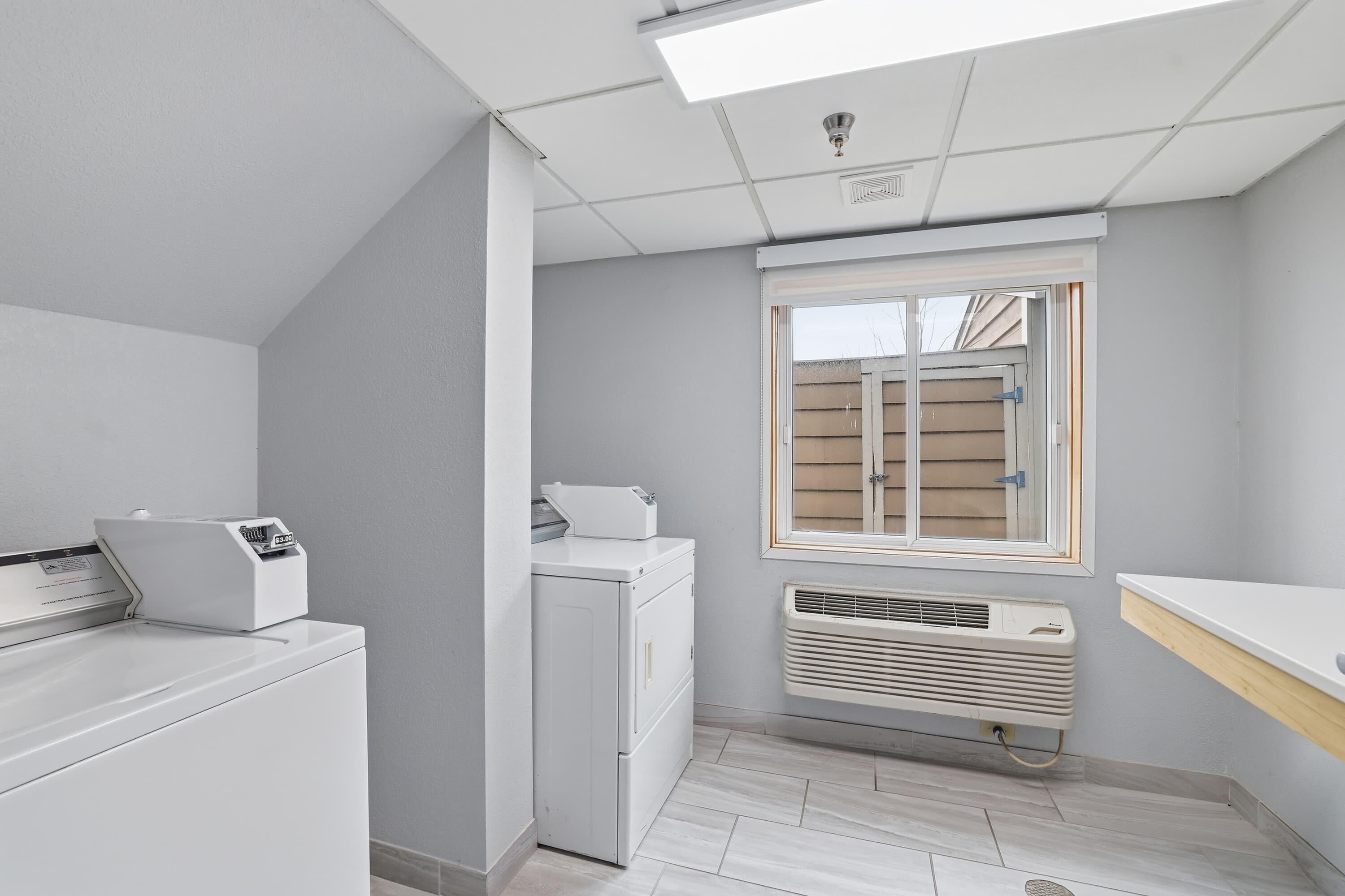 Une buanderie équipée d’un lave-linge, d’un sèche-linge et d’un climatiseur à évacuation.