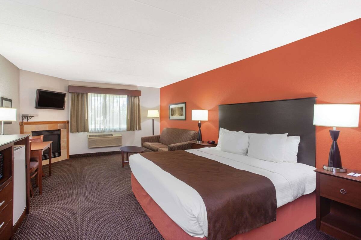 Une chambre d’hôtel équipée d’un lit, d’un bureau, d’une chaise, d’une télévision et d’une cheminée.
