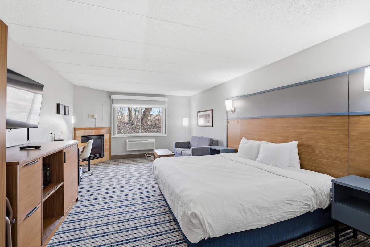 Une chambre d’hôtel équipée d’un lit, d’un bureau, d’une chaise, d’une télévision et d’une cheminée.