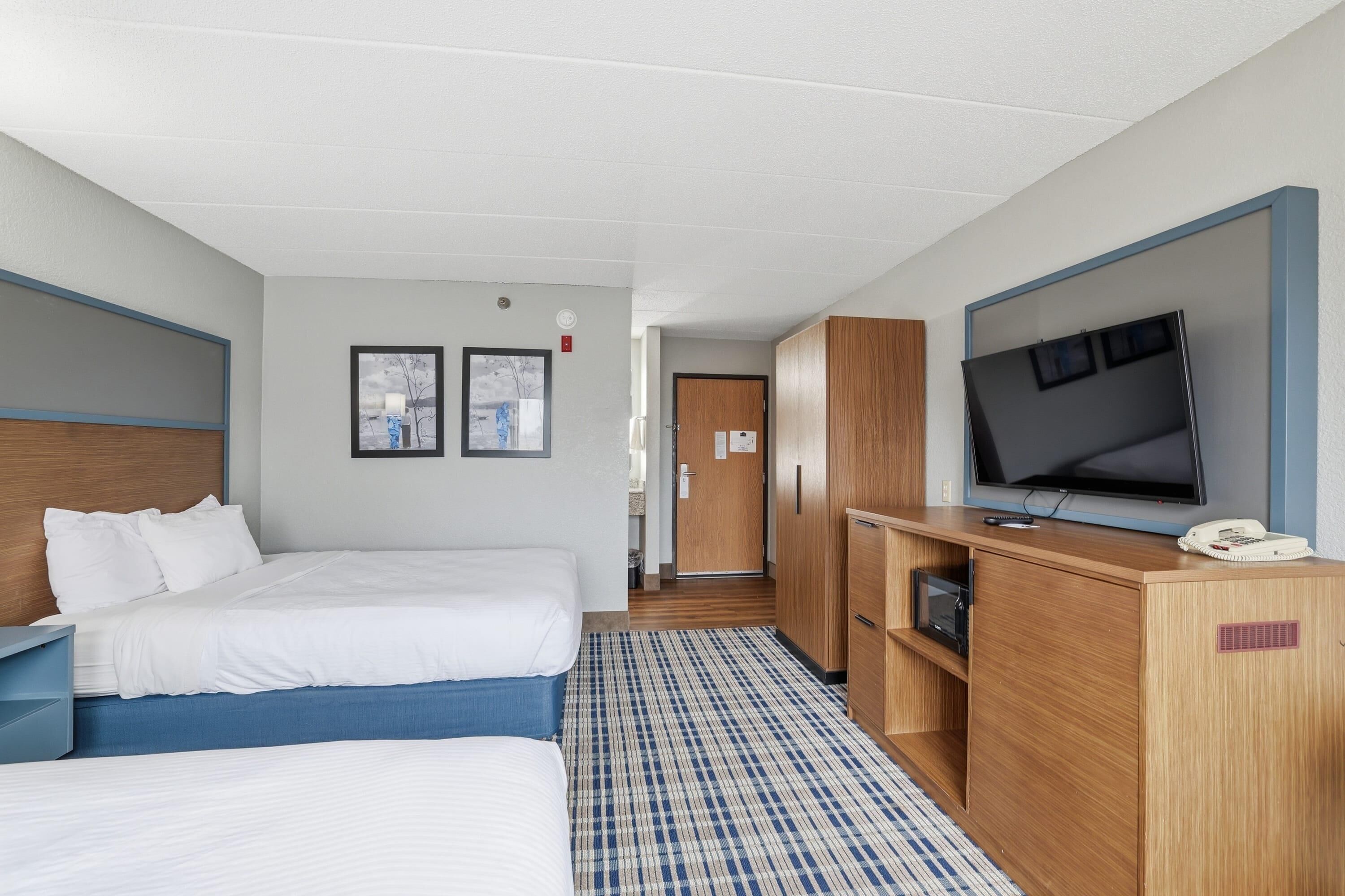 A hotel room with two beds, a TV, a desk, and a wardrobe.