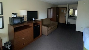 A hotel room with a kitchenette, a sofa, a TV on a wooden cabinet, and a bed. - Cobblestone Hotel & Suites – Wisconsin Rapids (Wisconsin Rapids)
