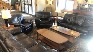A living room with leather sofas, a glass coffee table, and lamps. - Cobblestone Hotel & Suites – Wisconsin Rapids (Wisconsin Rapids)