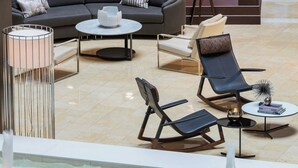 Un espace de détente moderne comprenant un canapé, des fauteuils, une petite table et un lampadaire.