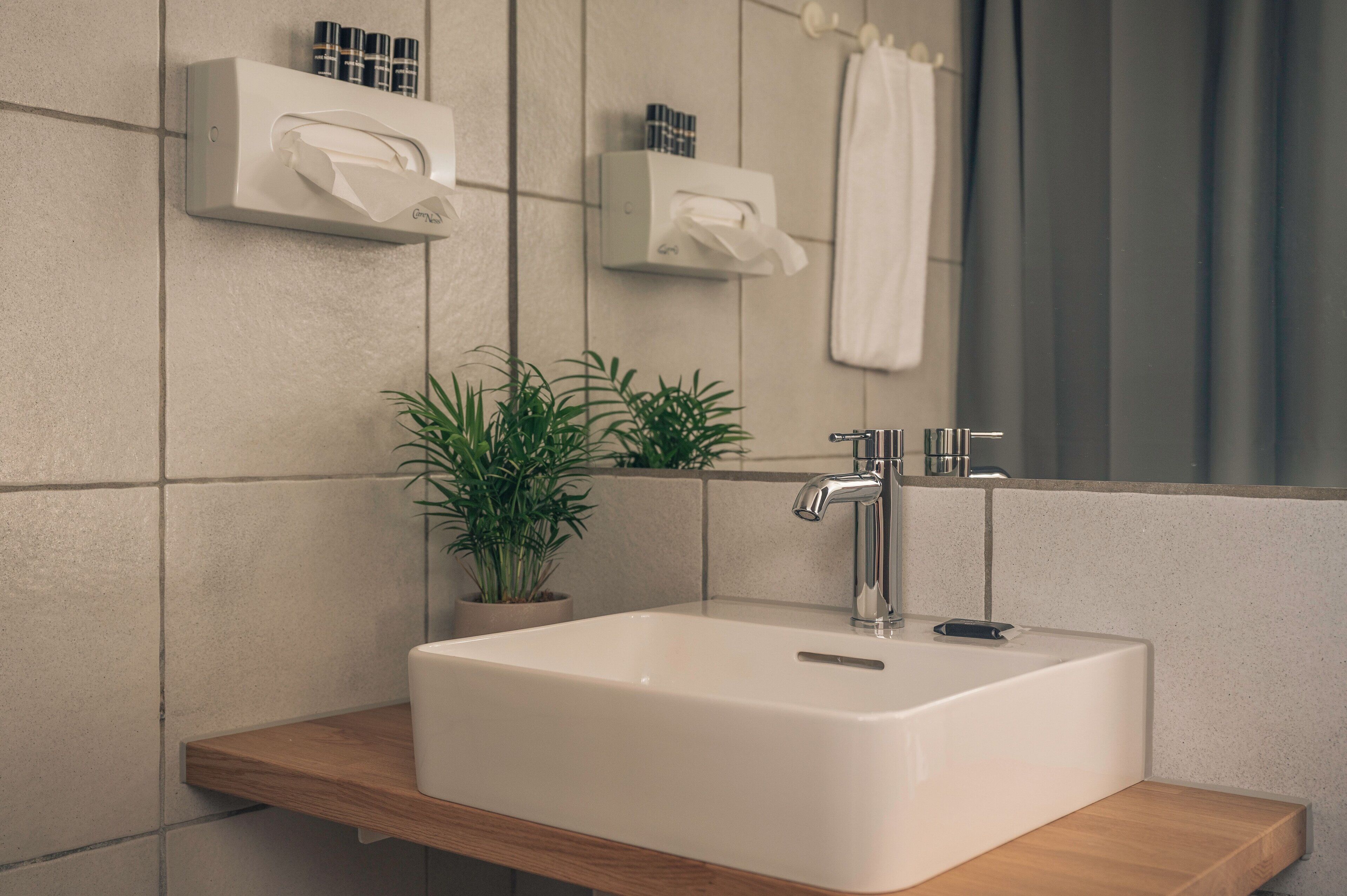A bathroom with a white sink, a mirror, and two wall-mounted towel dispensers.