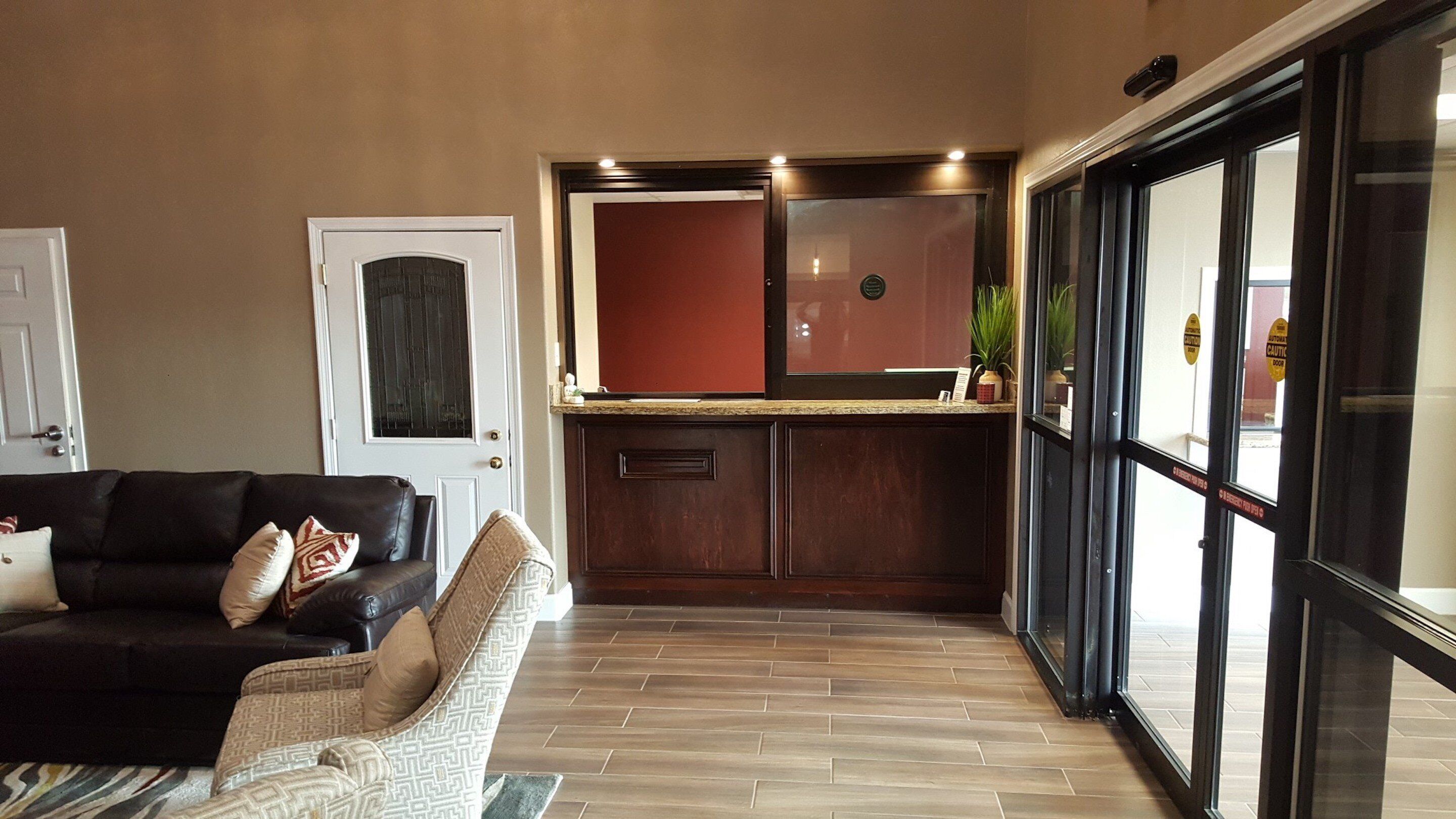 Una sala de estar con un sofá y un sillón estampado, una zona de cocina con un armario rojo, y un ventanal corredero que da al exterior.