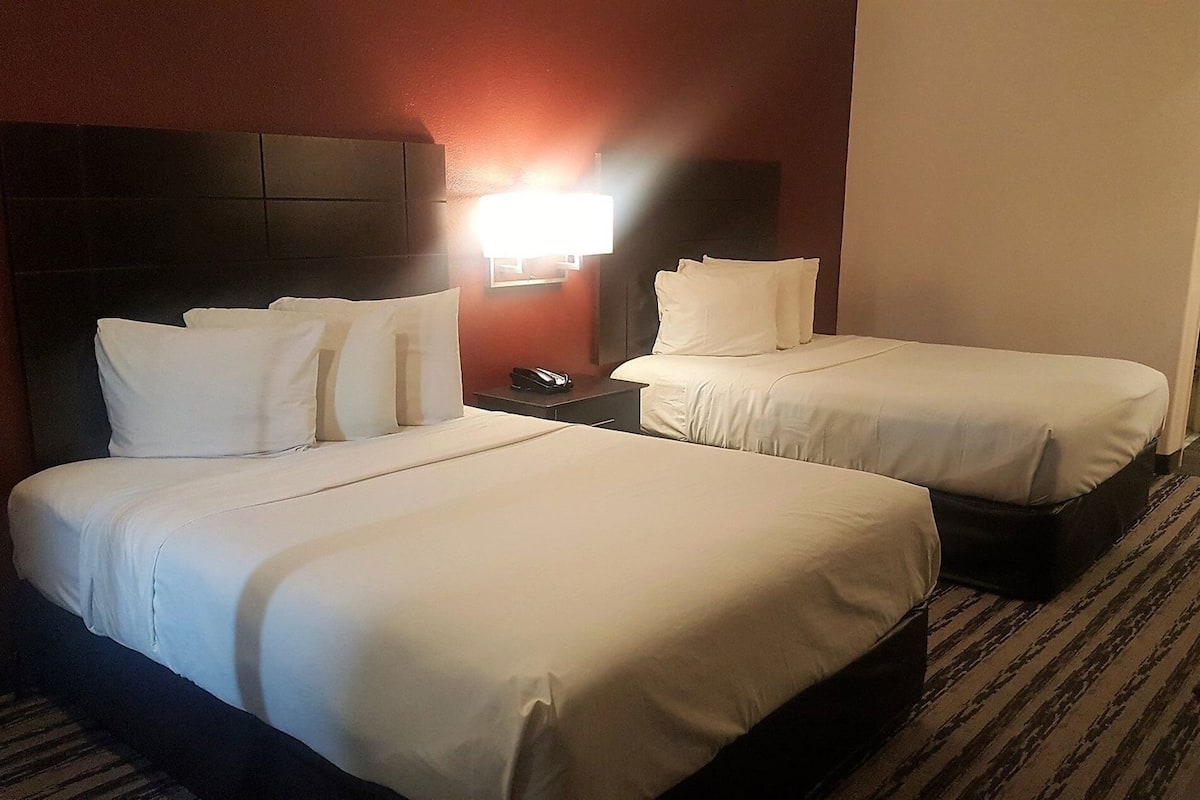 Une chambre d’hôtel avec deux lits, une table de chevet, une lampe et un téléphone.