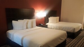 A hotel room with two beds, a nightstand, and a wall-mounted lamp.