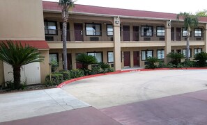 Un motel à plusieurs étages doté de balcons, d’un parking et d’une bordure rouge signalant l’interdiction de se garer.