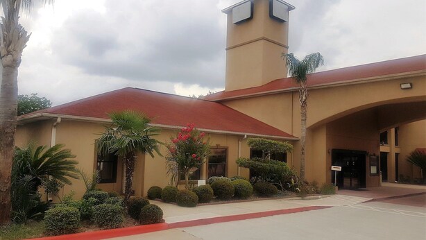 A building with a red roof, a central tower, and a covered entrance.