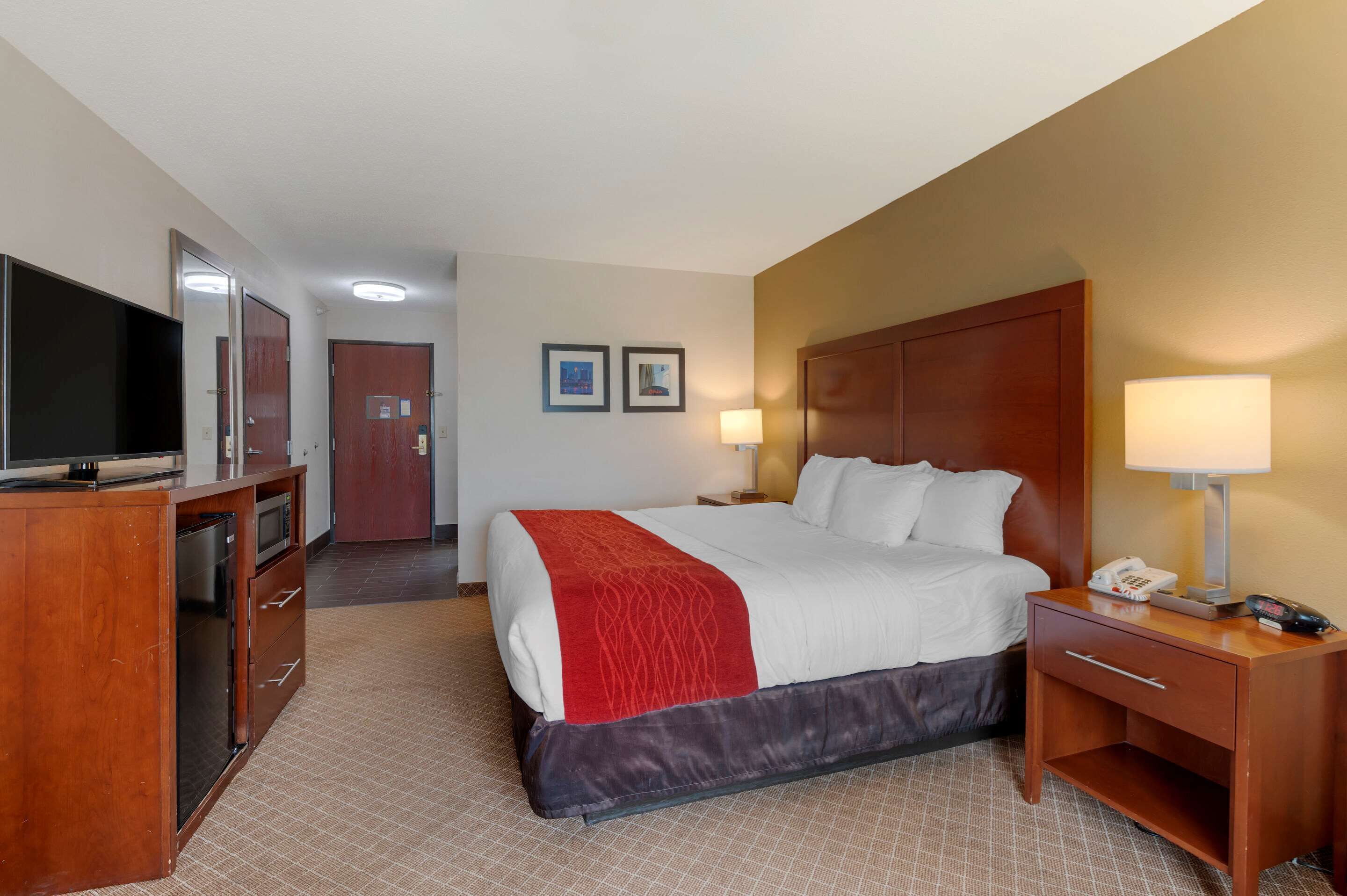 Ein Hotelzimmer mit Bett, Schreibtisch, Fernseher und Spiegel.