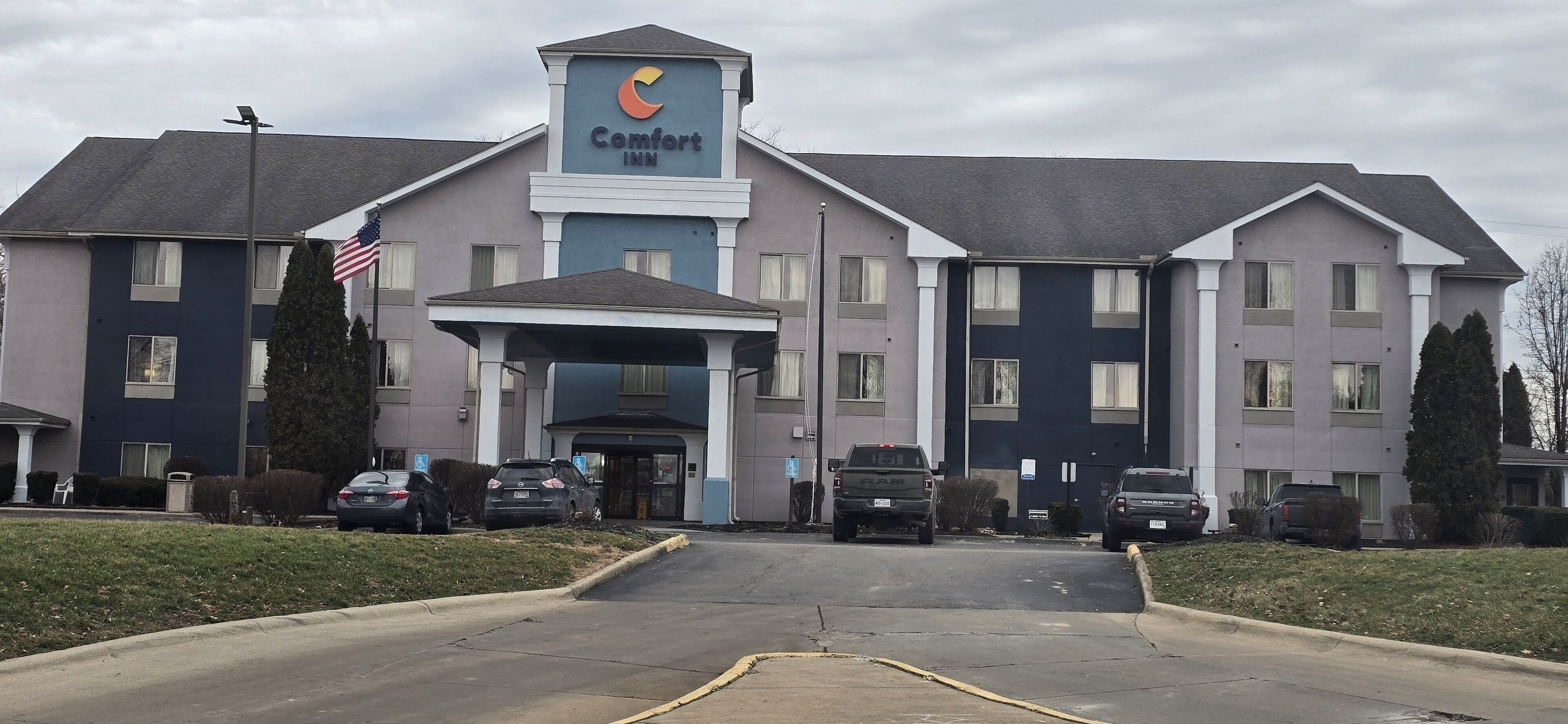 Un hôtel Comfort Inn doté d’une entrée principale, de nombreux espaces de stationnement et d’un drapeau américain.