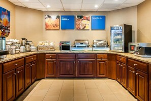 A breakfast bar with various food items and appliances.