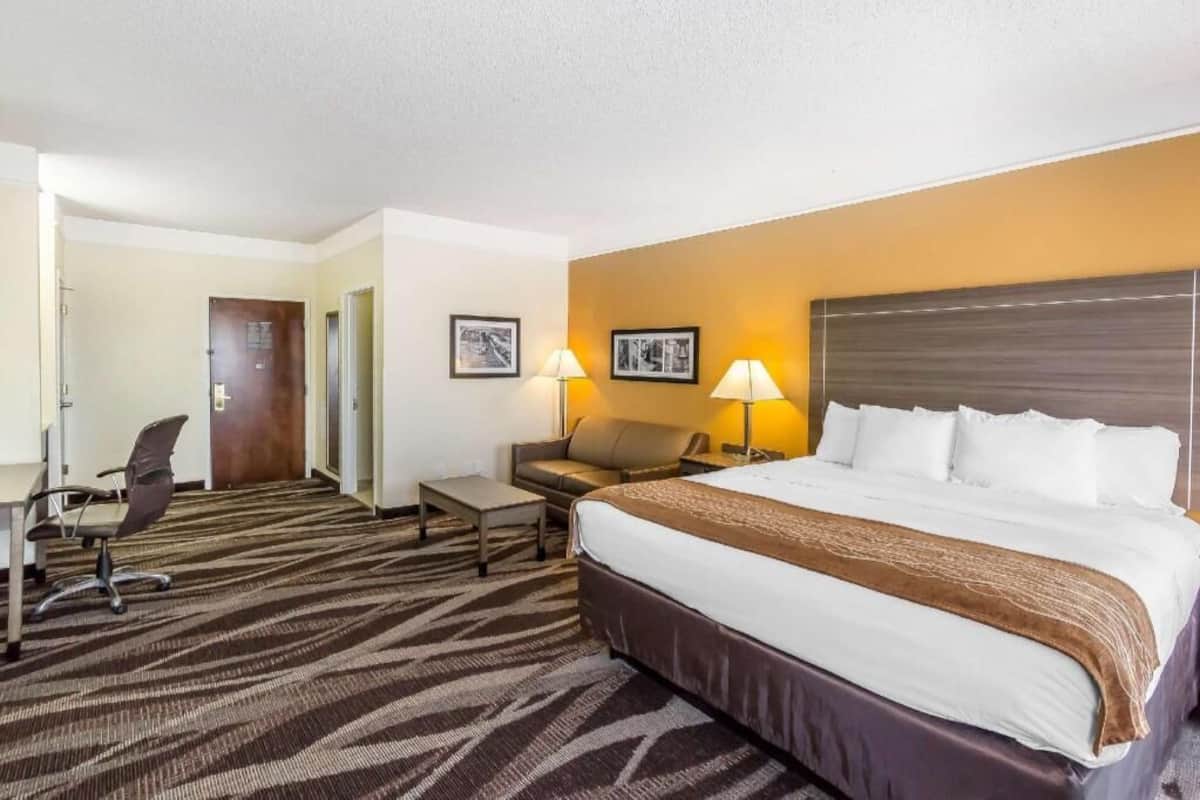 Een hotelkamer met een groot bed, een bureau, een stoel, twee lampen en een bank.