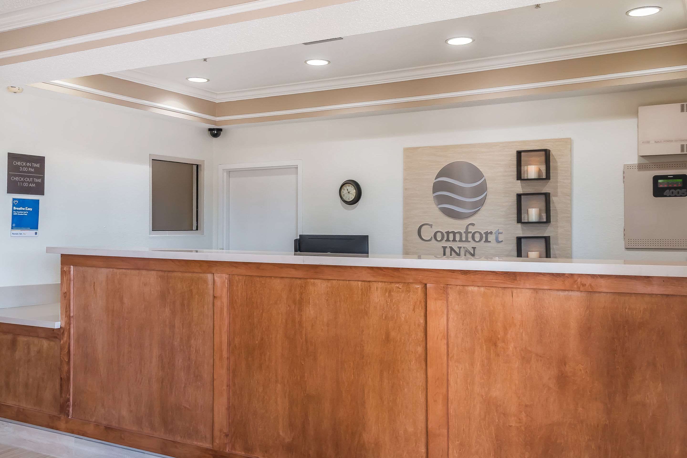 A reception area with a wooden reception desk, a clock, and a sign that reads "Comfort Inn."