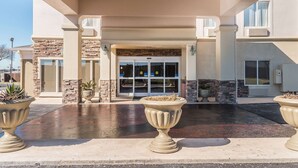A building entrance with a stone facade, large windows, and potted plants. - Comfort Inn near Frost Bank Center (San Antonio)