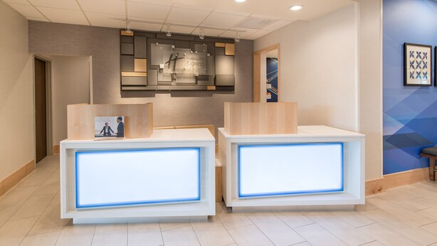 Un espace d’accueil doté de deux comptoirs de réception, d’un luminaire moderne et d’un motif géométrique sur le mur.