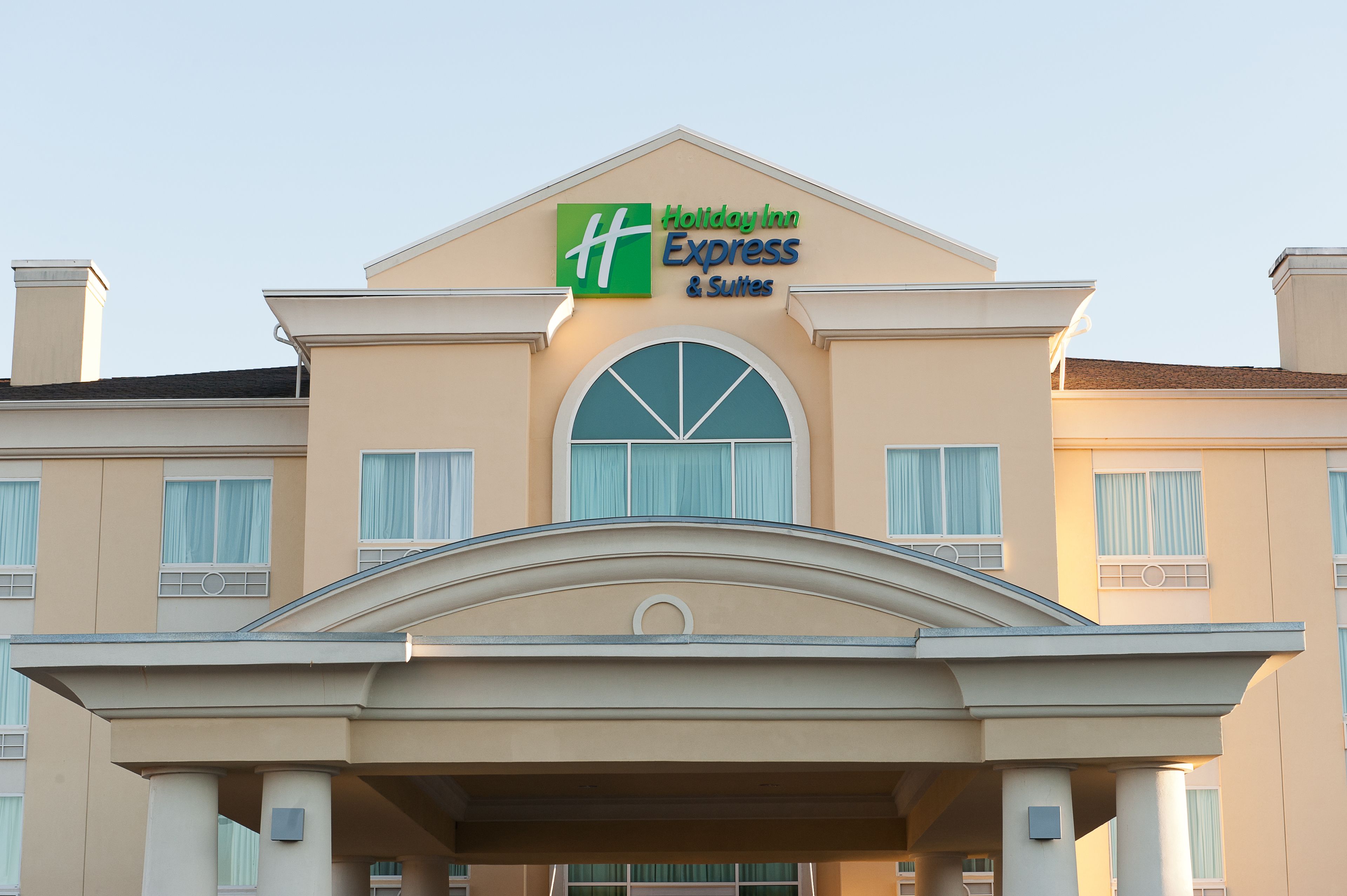 Edificio de Holiday Inn Express & Suites con un letrero llamativo, amplias ventanas y un acceso cubierto.