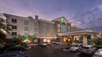A hotel with a central entrance, multiple parking spaces, and a covered area for drop-offs.