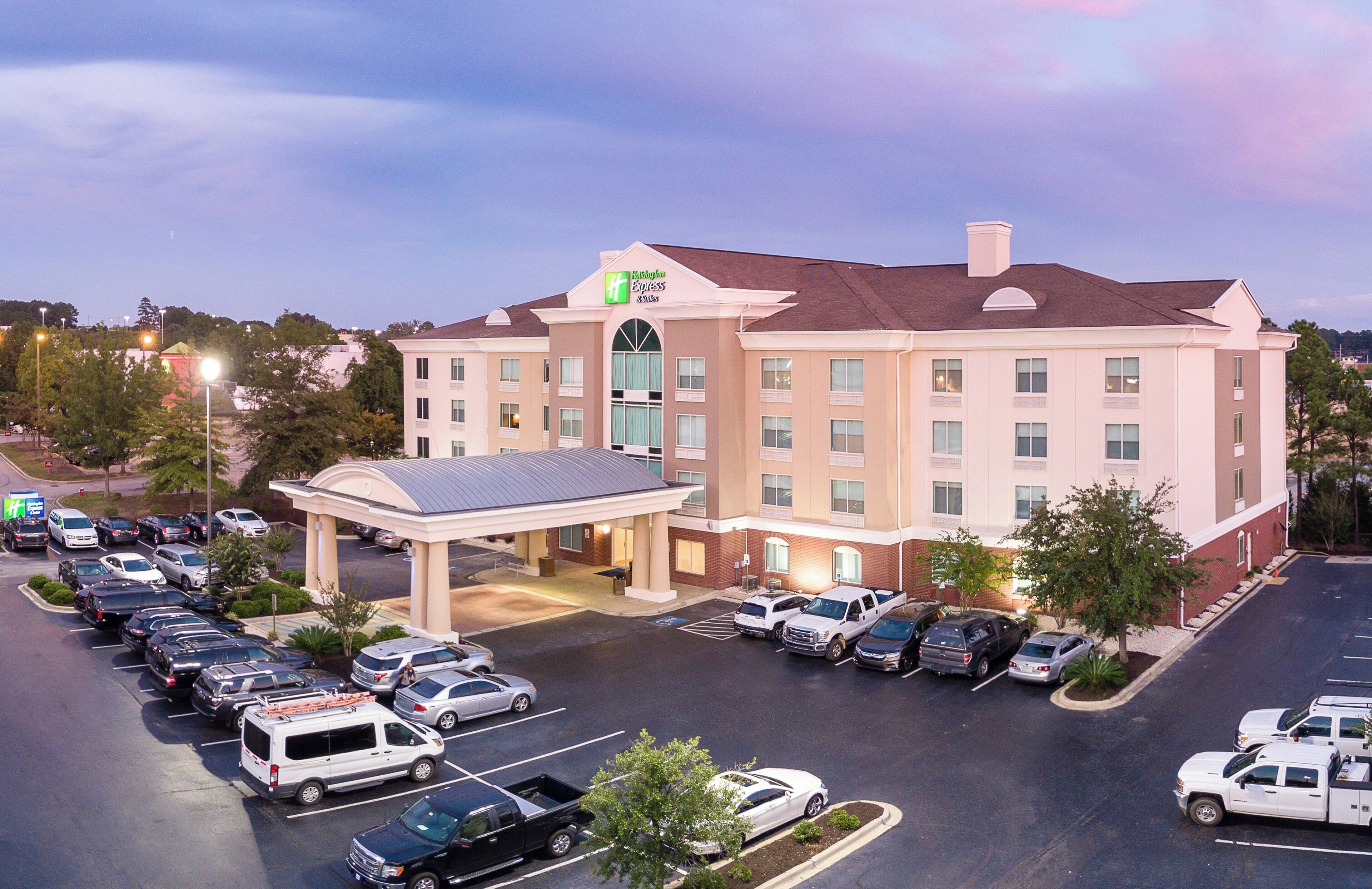 A Holiday Inn Express hotel with a parking lot full of cars, a covered entrance, and a large building with multiple windows.