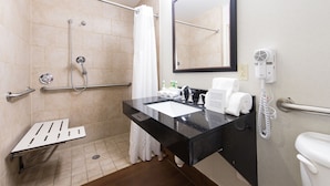 Une salle de bain équipée d’une douche, d’un lavabo, d’un miroir, de toilettes et d’un téléphone.