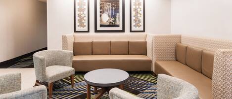 Een hotel lobby met een bank, fauteuils en een salontafel.