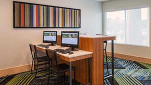 Un espace de travail équipé de deux ordinateurs, d’un bureau, de chaises et d’un tapis aux couleurs vives.