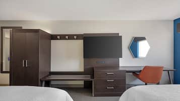 Una habitación de hotel con cama, escritorio, silla, armario y televisor.