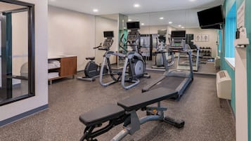 A gym with treadmills, elliptical machines, and a bench.
