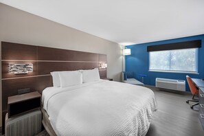 A hotel room with a large bed, a desk, a chair, a window, and a wall-mounted lamp. - Holiday Inn Express - Balloon Fiesta Park by IHG (Albuquerque)