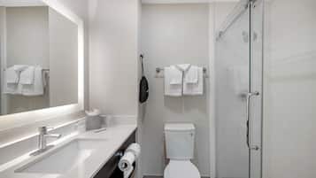 A modern bathroom with a white sink, toilet, and glass shower enclosure.