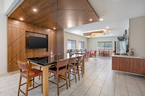 A modern kitchen with a large island, wooden cabinets, and a flat-screen TV mounted on the wall. - Holiday Inn Express - Balloon Fiesta Park by IHG (Albuquerque)