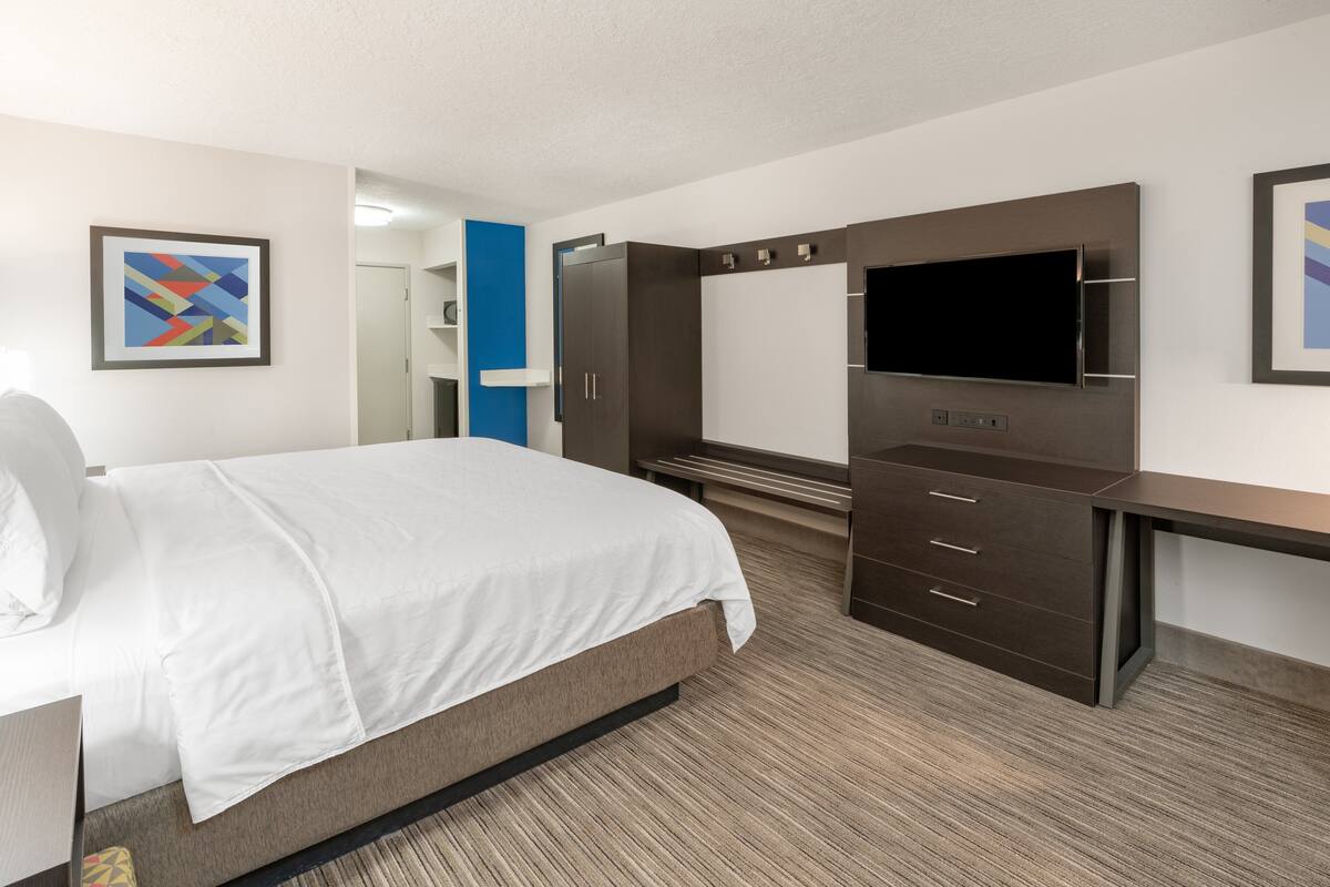 Une chambre d’hôtel équipée d’un lit, d’une télévision, d’un bureau et d’une armoire.