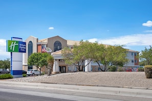 A Holiday Inn Express & Suites hotel with a modern design, featuring a prominent American flag and a clear blue sky. - Holiday Inn Express - Balloon Fiesta Park by IHG (Albuquerque)