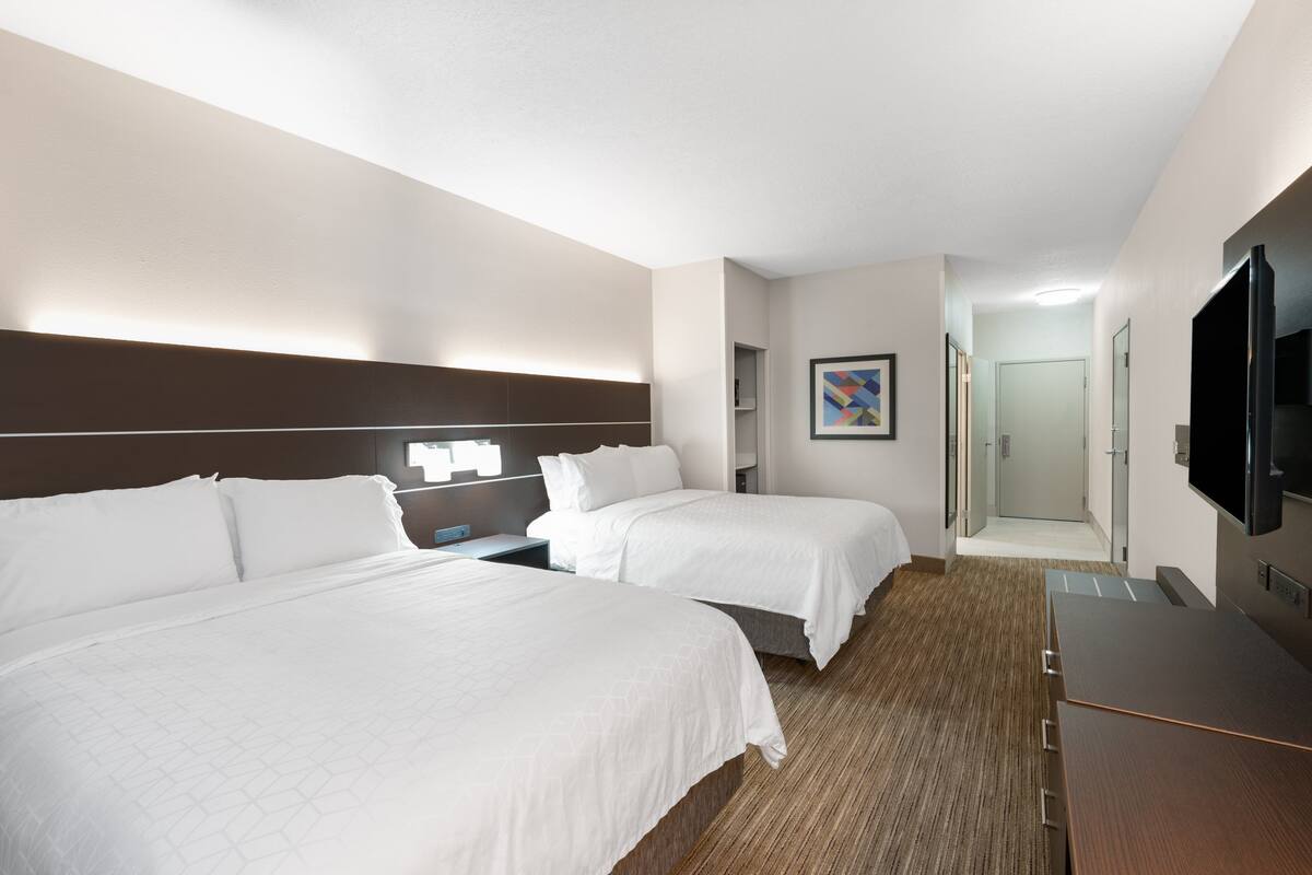 Une chambre d’hôtel avec deux lits, une télévision, un bureau et un espace douche.