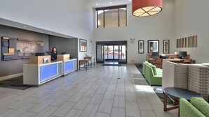 Un hall d’entrée spacieux avec un comptoir d’accueil, un espace salon et de grandes fenêtres.