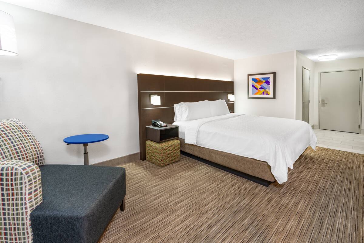 Une chambre d’hôtel avec un lit, une petite table, une chaise et une table de chevet.