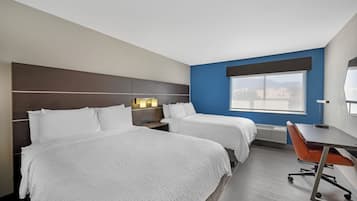 Ett hotellrum med två sängar, ett skrivbord och en stol.