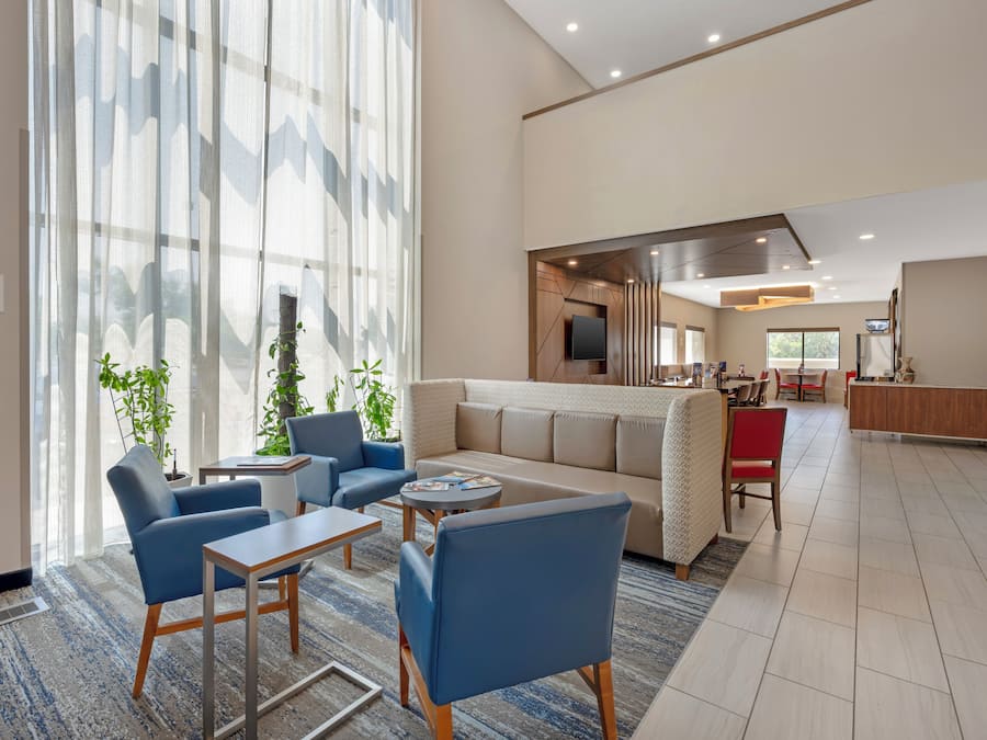 A modern hotel lobby with a seating area, a kitchen in the background, and a large window with a view.