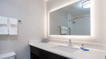 Een bad/douchecombinatie, een haardroger, handdoeken